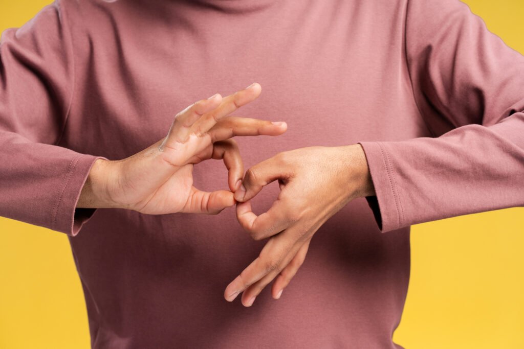 Close up man learning sign language to talk over yellow background in studio. Sign language concept